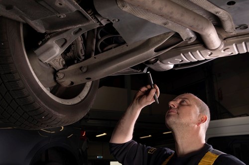 ServiceOnly monteur met lamp onder auto