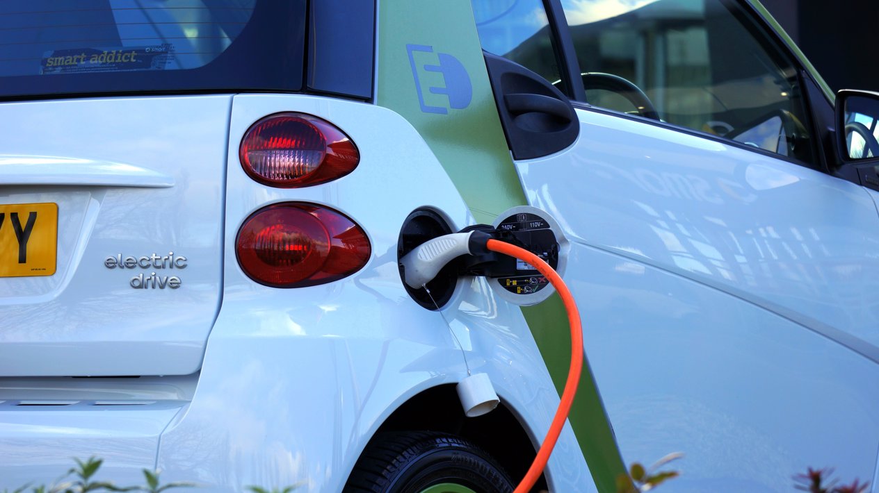Een elektrische auto met een aangesloten oranje laadkabel