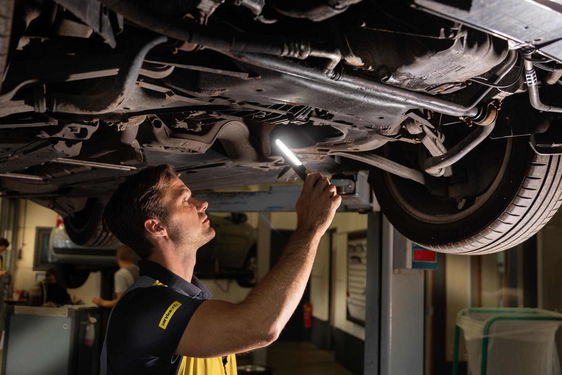 ServiceOnly monteur onder auto met zaklamp